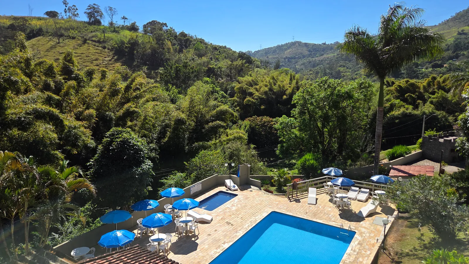 A pousada vista de cima, com as piscinas, os chalés e as montanhas em volta