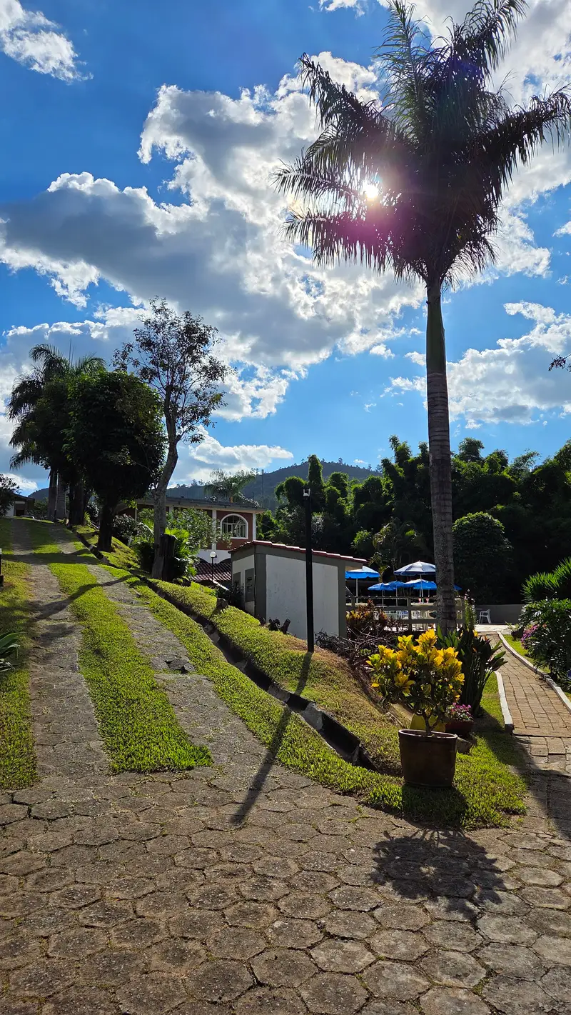 Caminho gramado entre os chalés, com a piscina e as montanhas ao fundo