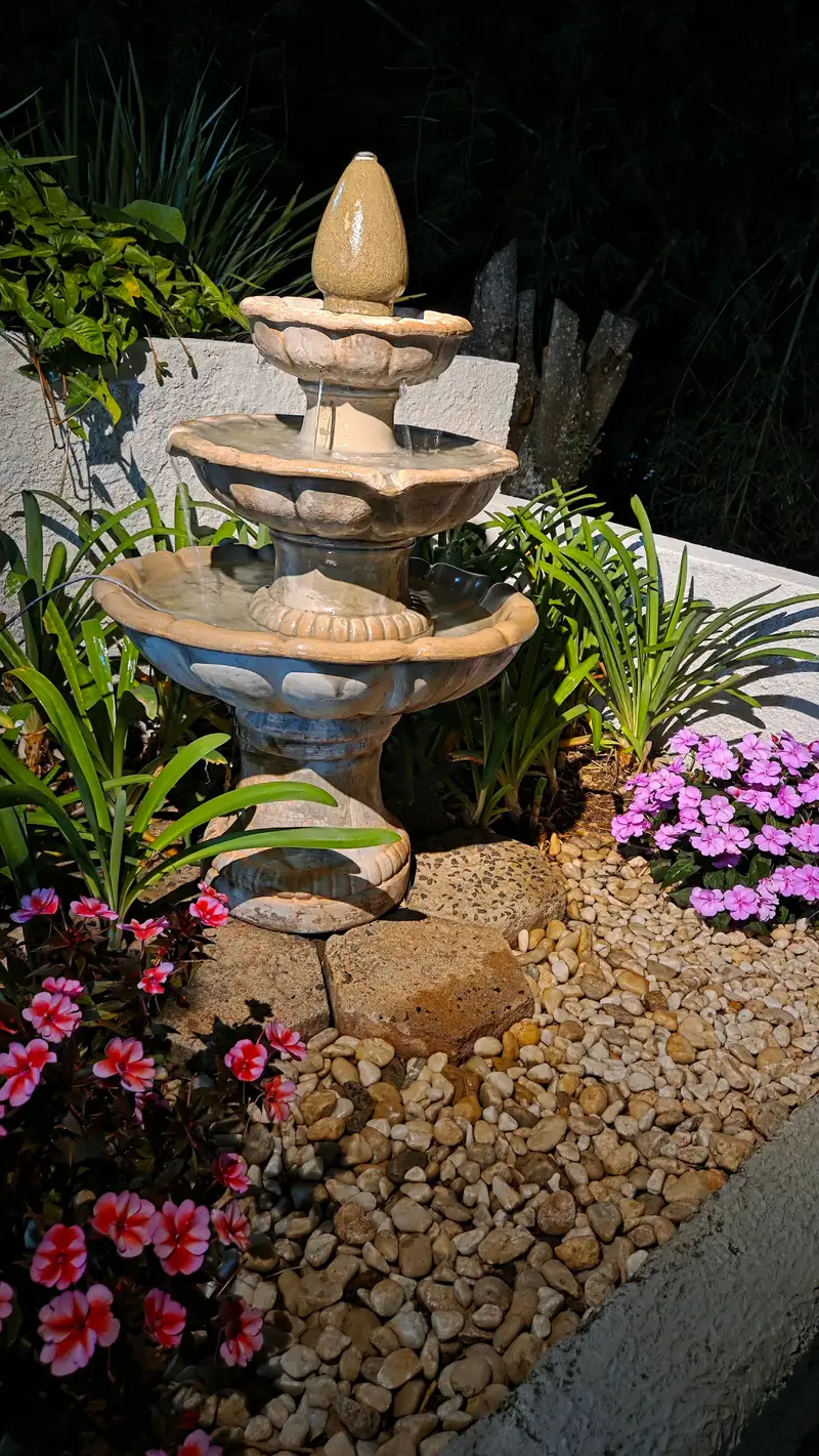 Fonte de pedra cercada de flores no jardim da pousada