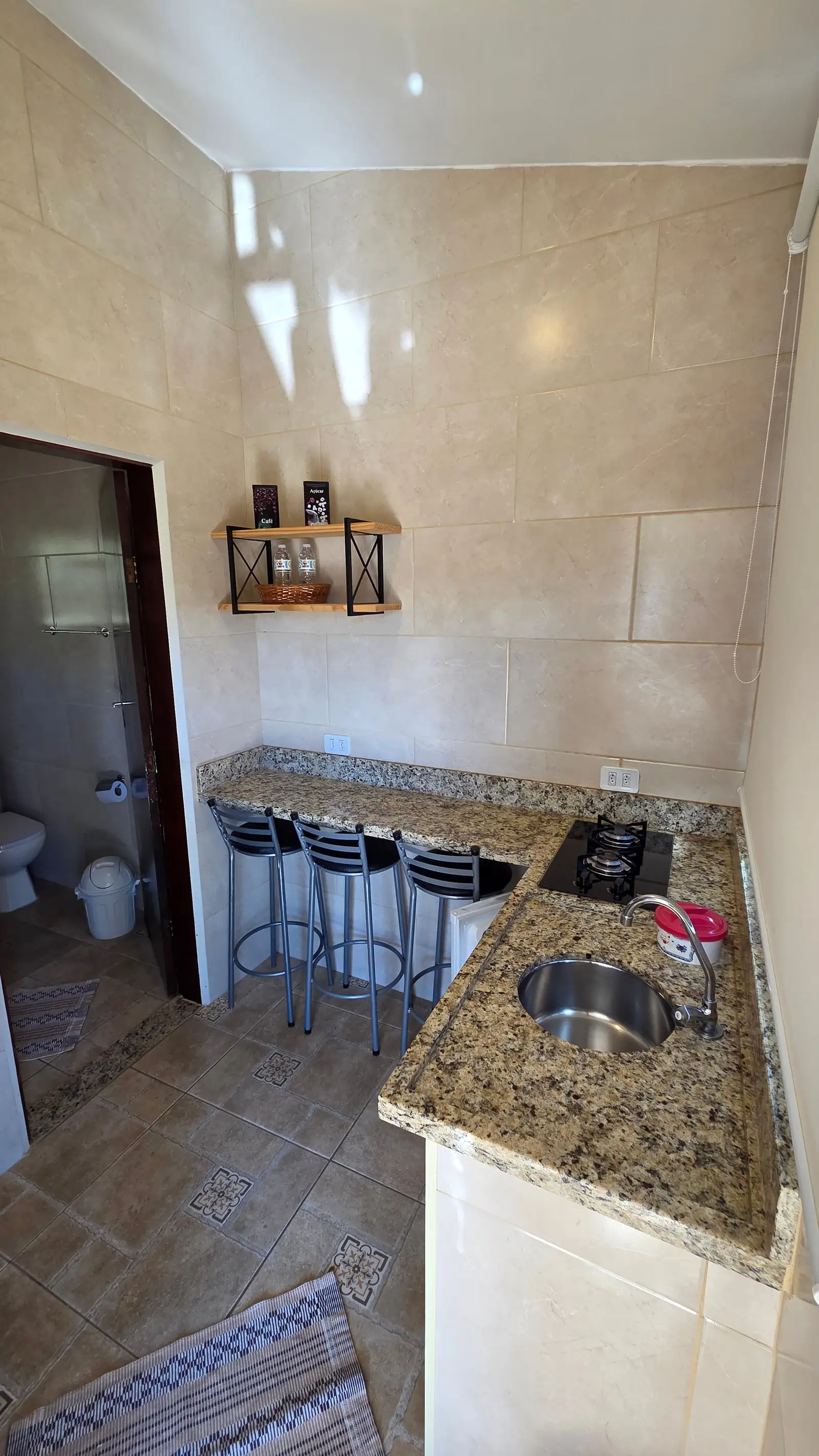 Cozinha do Chalé Master, com cooktop, pia e banquetas encostadas na bancada