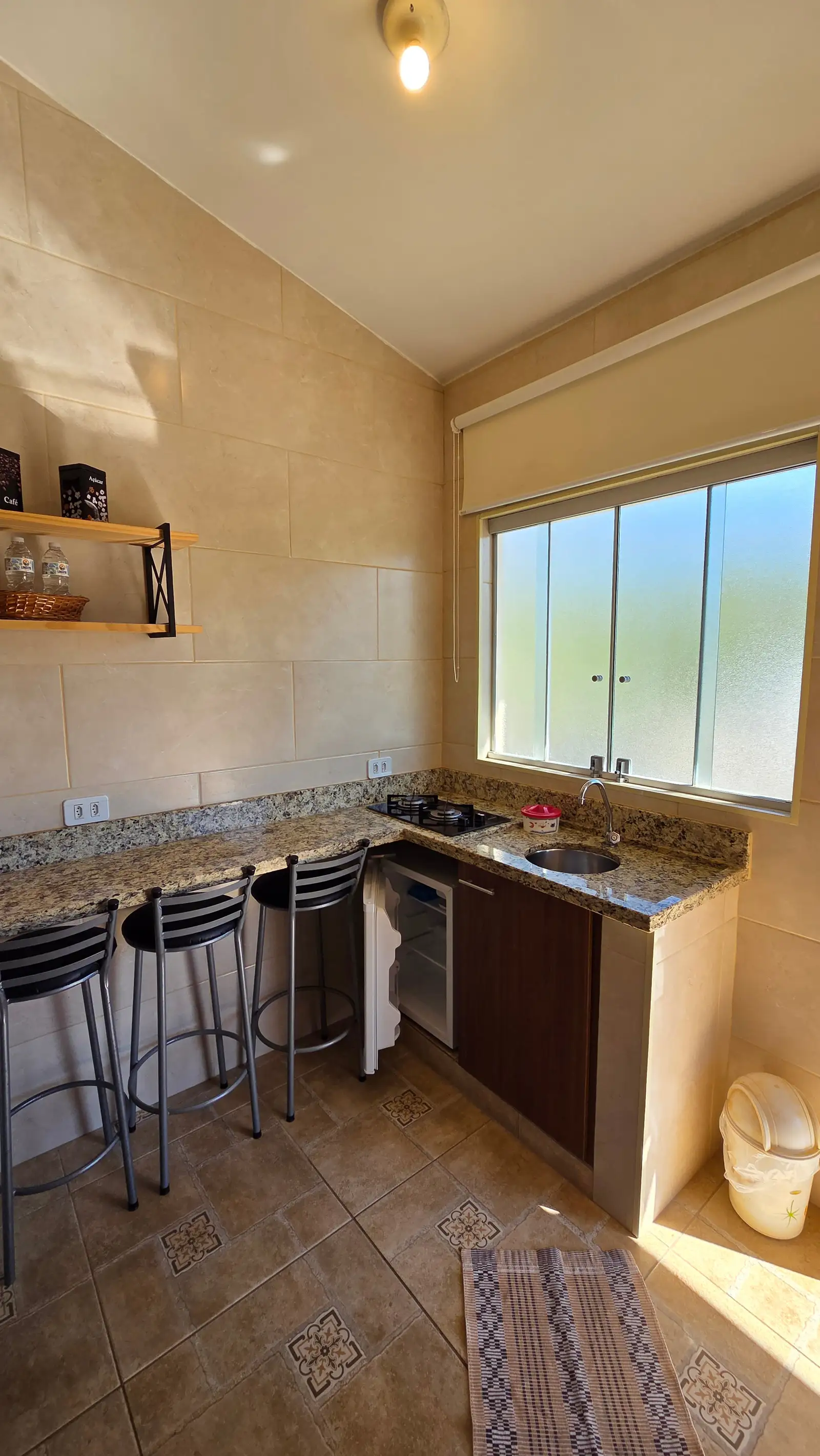 Cozinha do Chalé Master vista da janela, com cooktop, forno e pia de granito