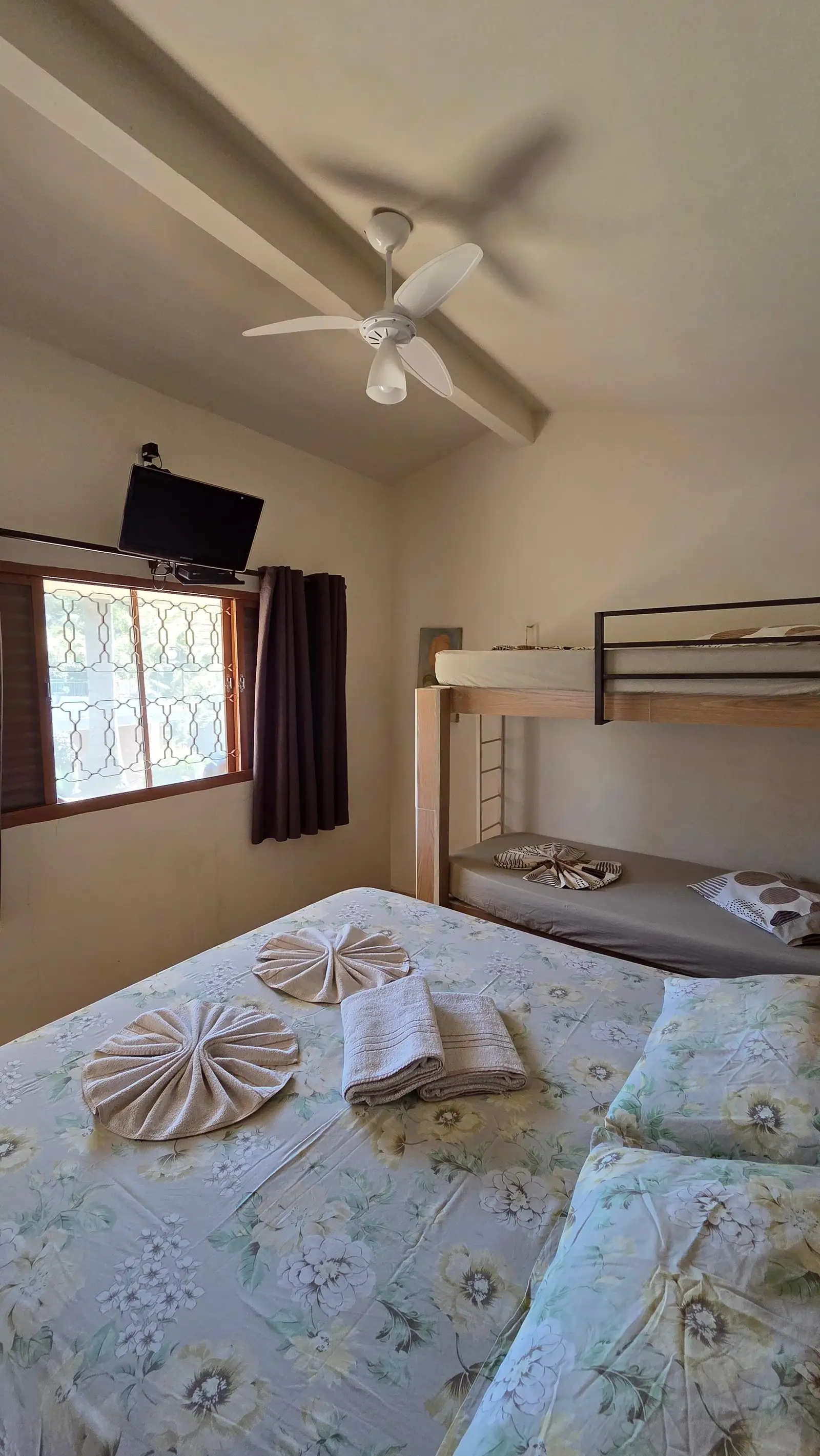 Quarto do Chalé Master, com janela, cortina e o beliche ao lado da cama