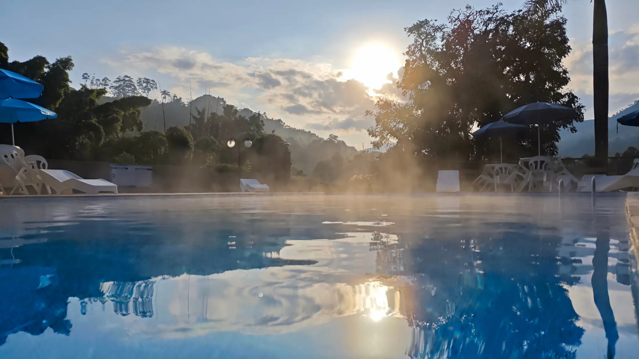 Piscina aquecida da pousada fumegando na primeira hora da manhã, com as montanhas ao fundo