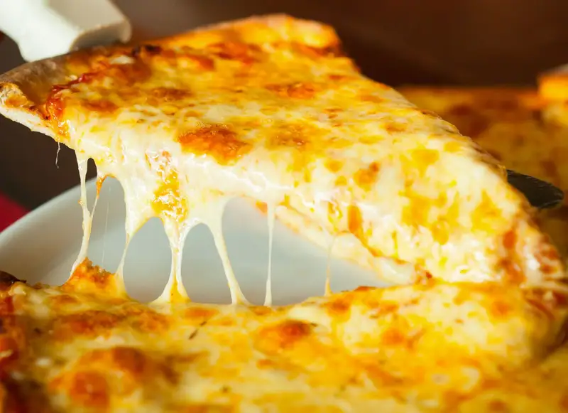 Fatia de pizza de mussarela sendo servida