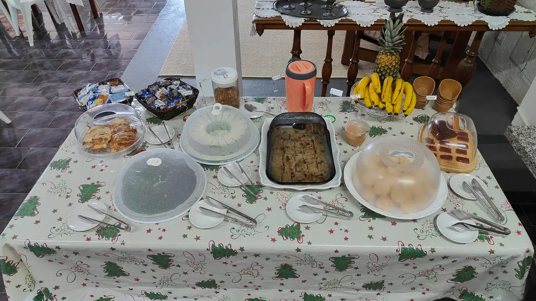 Mesa posta com pães, bolos, frutas e o café da manhã servido