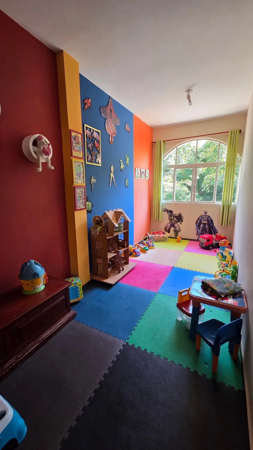 Sala Kids, com brinquedos, prateleiras e tapete colorido no chão