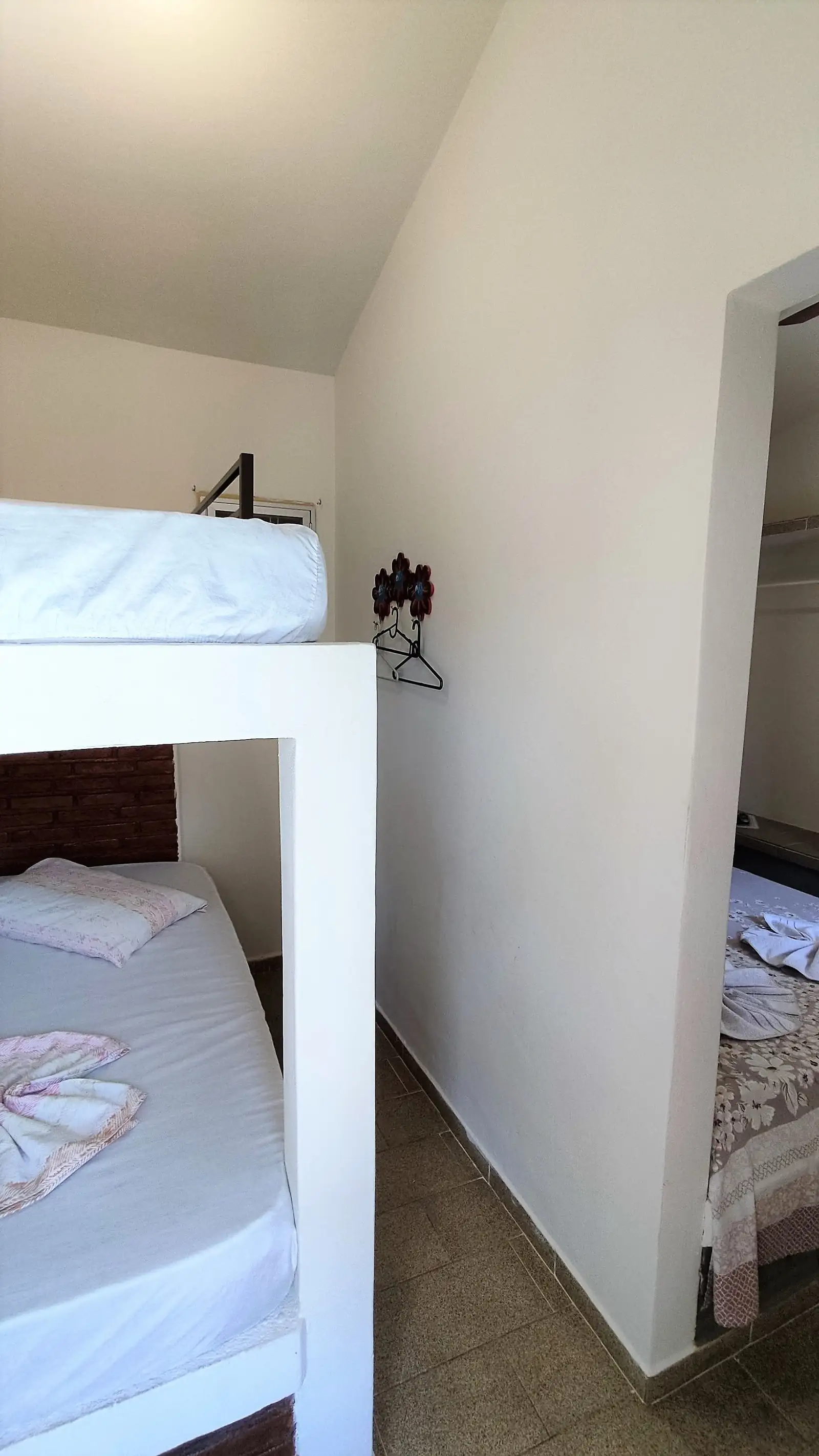 Beliche do Chalé Standard sobre a cama, com cabides ao lado