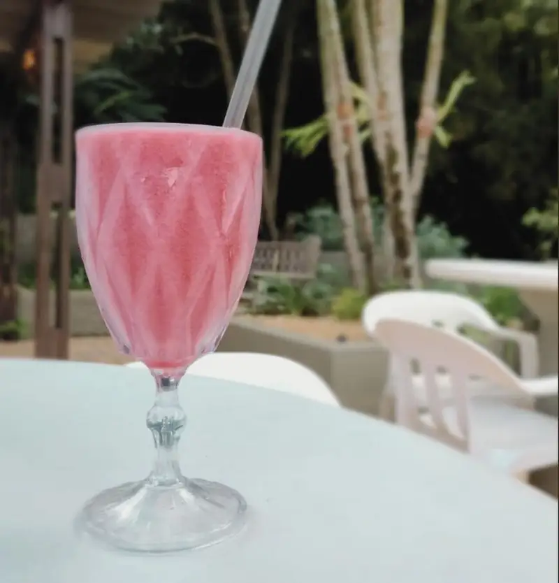 Taça de vitamina de morango com canudo, na mesa do jardim